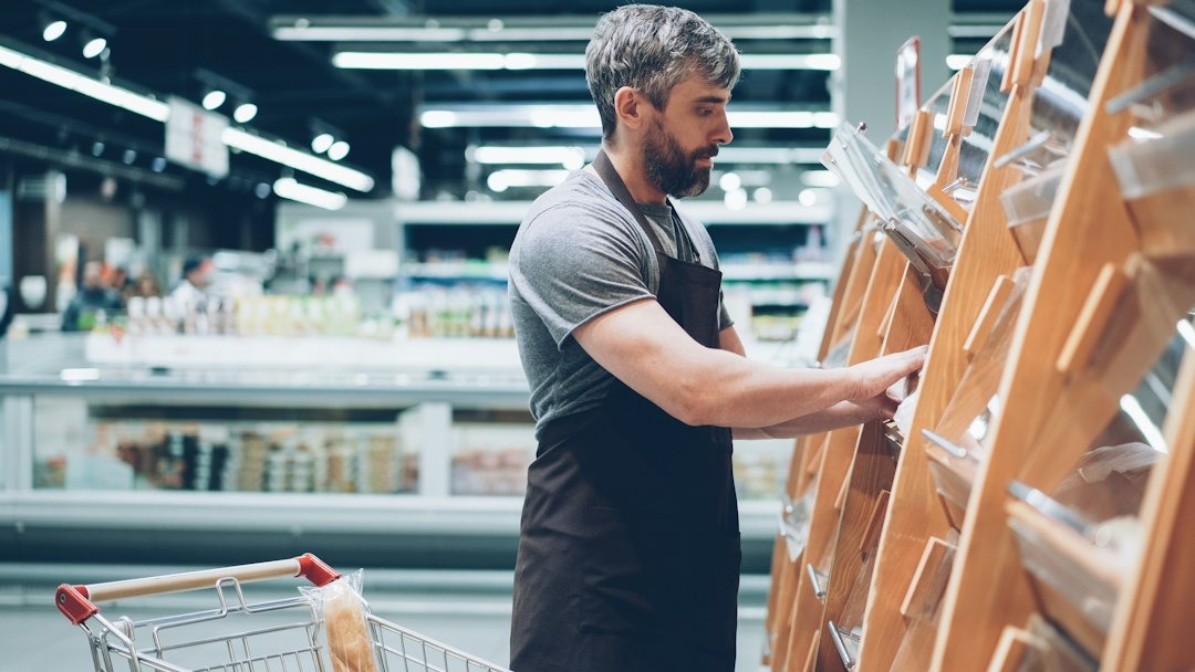 Man comparing grocery products while learning how to cut your grocery bill
